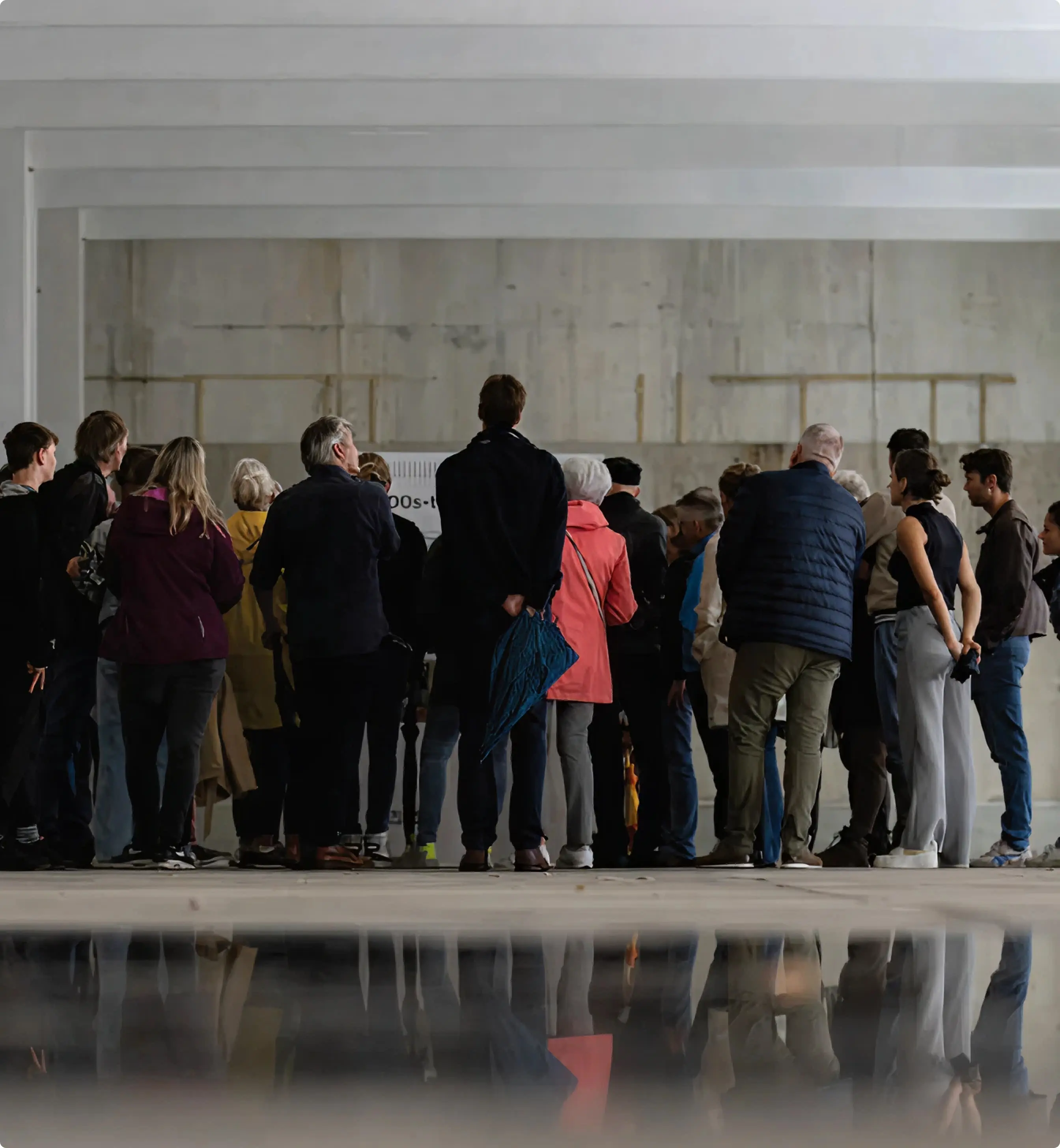 Group of visitors exploring a spacious industrial hall during an architectural site tour.
